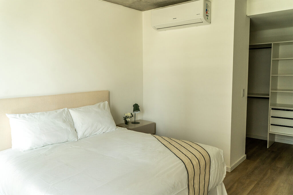 Dormitorio con aire acondicionado split y vestidor abierto visible, garantizando la climatización y espacio.