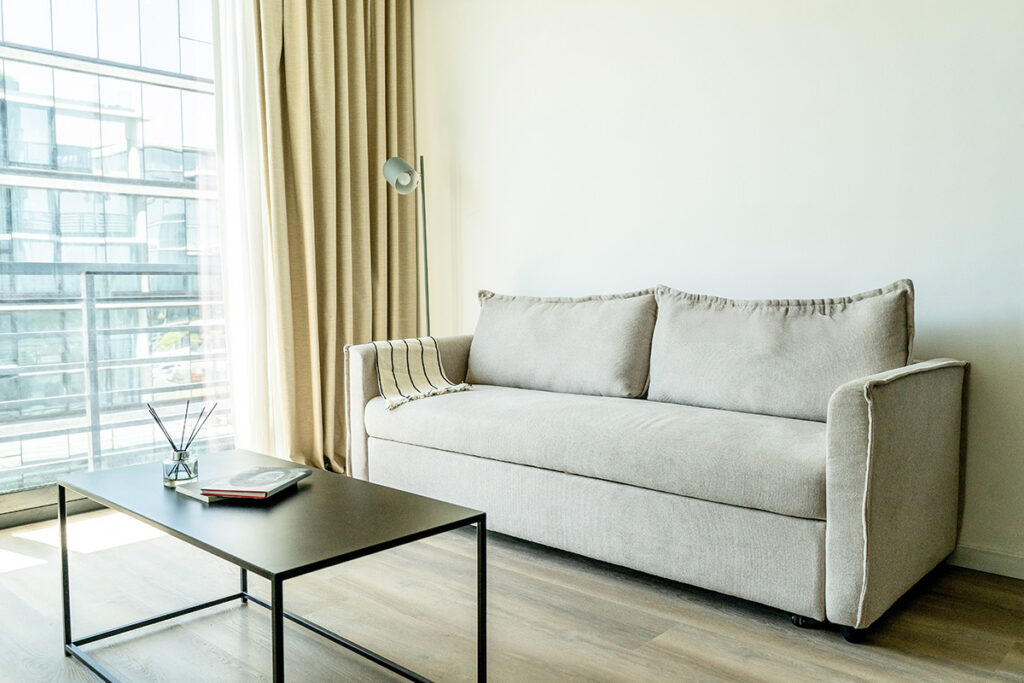 Sofá beige de tres cuerpos, mesa de centro negra y difusor de aromas, bañado en luz natural de la ventana.