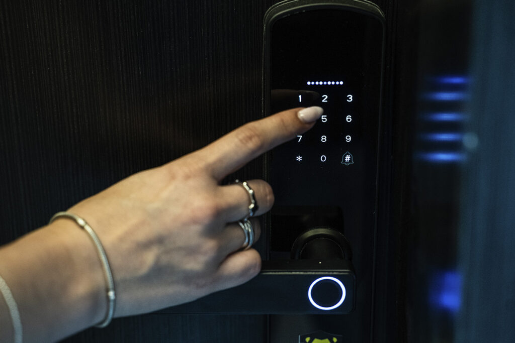 Primer plano de una mano ingresando el código en la cerradura digital de la puerta, indicando acceso seguro.